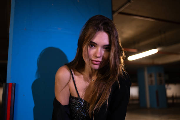 A well-dressed, beautiful young blonde woman posing in an underground parking lot.