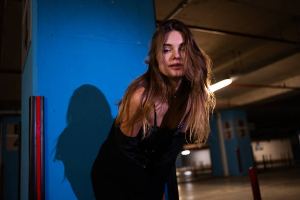 A fashionable Caucasian woman posing on a city street, wearing a black dress