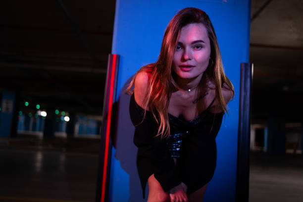 A well-dressed, beautiful young blonde woman posing in an underground parking lot.