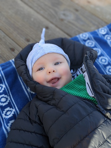 A baby rests on a fleece blanket during a rest on a family hike in winter.