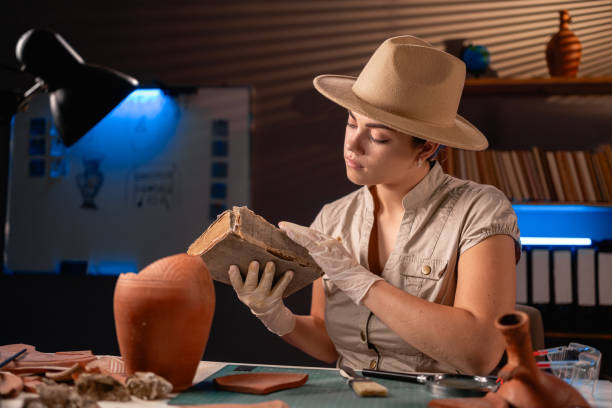 istock Archeologist reading old book working late night in office and studying amphora. 1997083439