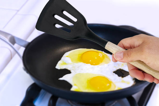 istock hand holding a Slotted Turner with eggs in a frying pan 1997083613
