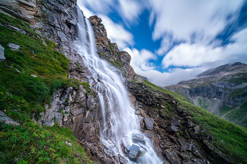 beautiful waterfall in the mountains in austria on summer day with some clouds no people, long exposure