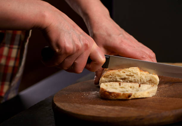 istock Fresh bread on table close-up. Fresh bread on the kitchen table Whole grain bread put on kitchen wood plate with a chef holding knife for cut. The healthy eating and traditional bakery concept. Front viev. 1997132062
