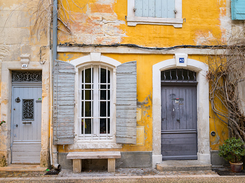 Arles, France - March 7, 2023: Yellow facade and entrance of an old house in Arles