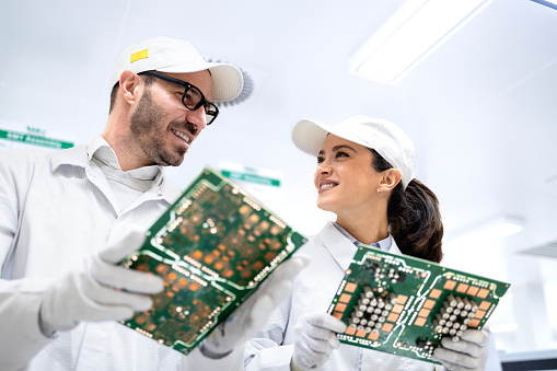 Engineering technologist holding printed circuit boards and developing electronics components.