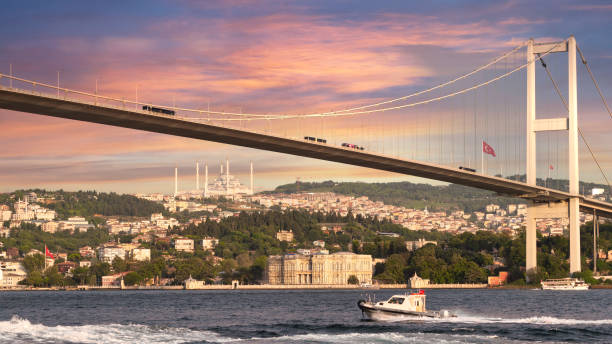 istock Sailboat traverses the Bosphorus Strait beneath the iconic Bosphorus Bridge, bathed in the warm glow of the setting sun 1997194312