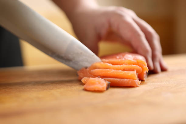 istock Red fish is cut into pieces with a knife on the board. 1997204095