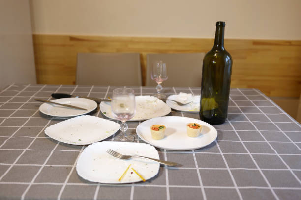 There are many dirty empty dishes and an empty bottle of wine on the table. Homework.