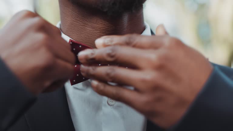 Hands, wedding and bowtie with a groom getting reading for his marriage ceremony outdoor at an event closeup. Fashion, luxury and a man dressing in a smart or formal suit for a celebration of love