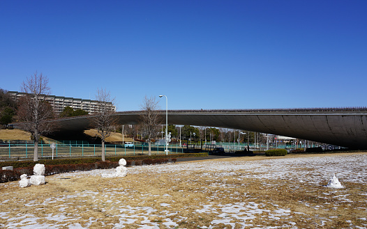 On a sunny day with some snow in February 2023, Kujirabashi Bridge in Inagi Central Park, with its beautiful curves reminiscent of the body of a whale, is located in Inagi City, Tokyo.