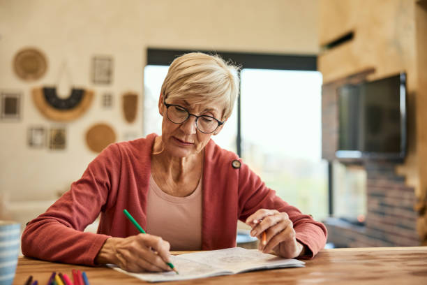 istock A mature woman holding and using crayons, coloring the coloring book. 1997243938