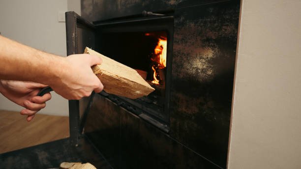 istock Heating home concept. Mans hand loading firewood into burning fireplace. Solid fuel and heating concept 1997249224