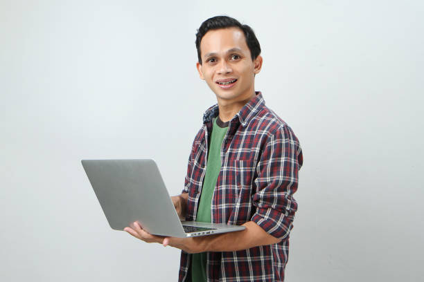 istock Happy asian indonesian man holding laptop computer on isolated background 1997255077