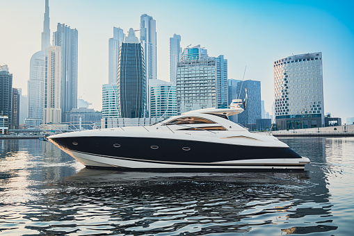 Luxurious motor yacht in deep blue sea of middle east showing skyline and sky scrappers