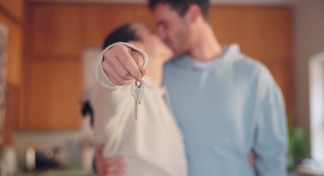 Couple, hands and kiss with keys in new home for moving together, property investment or real estate dream. Closeup, man and woman celebrate key to house building, financial security or mortgage loan