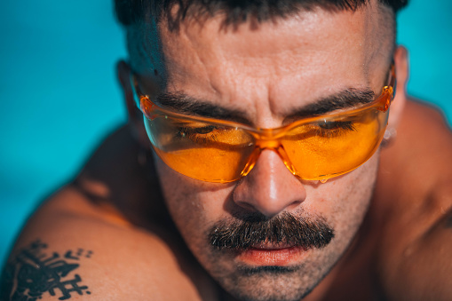 Handsome young urban man with sunglasses resting in the pool during a summer day