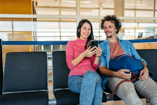 istock Young Couple Using A Phone Together While Waiting At The Airport 1997318975