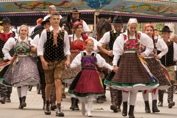 Villach, Austria - August 6, 2022: A group of people wearing traditional customes enjoy the procession of 'Villacher Kirchtag', the largest traditional folk festival in Austria, after some years of cancellation due to Covid.