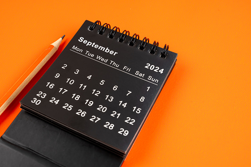 September 2024 desk calendar with pencil on orange color background.