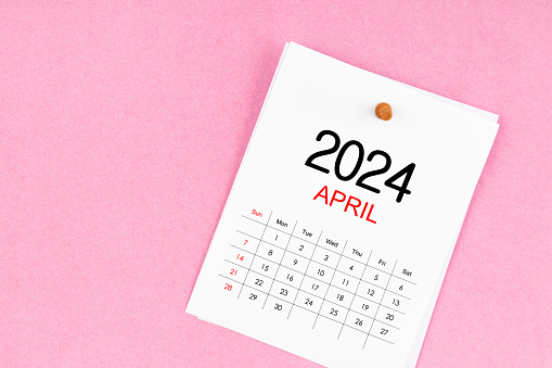 April 2024 calendar page and wooden push pin on pink Color background.