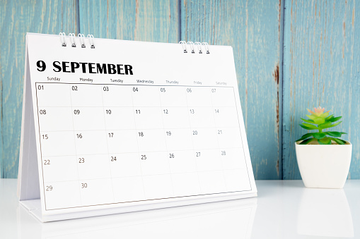 September 2024 calendar on the white table with blue wooden background.