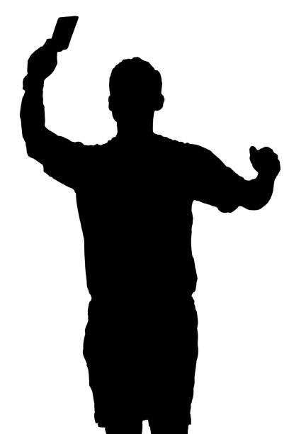 istock Silhouette of a referee in a ball game holding up a red card 1997345378