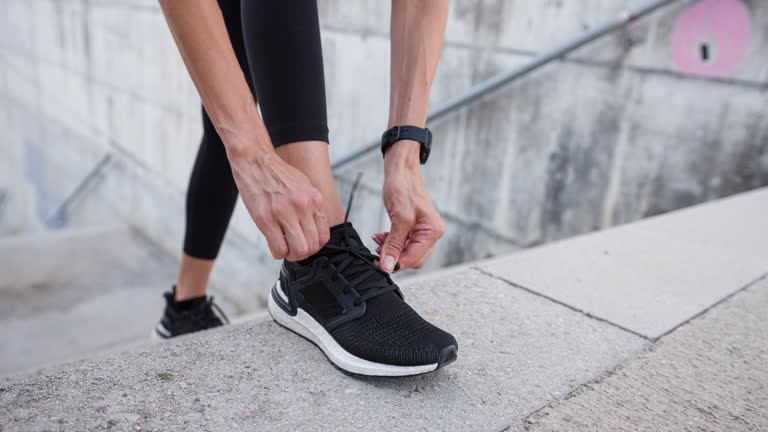 Athlete adjusts shoelaces, preparing for morning jog