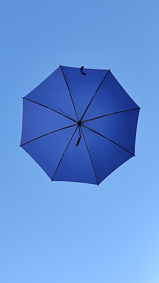 hanging blue umbrella seen from below in clear sky