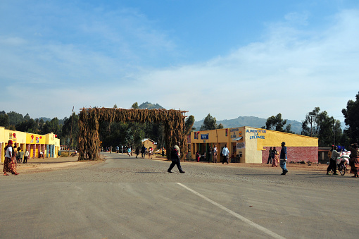 Hesha / Mukamira, Nyabihu District, Western Province, Rwanda: typical gate with green tree branches at the entrance to a neighborhood - small commerce on both sides, mountains in the background.