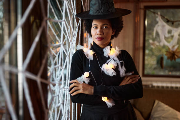 istock Black woman dressed as a witch with crossed arms on Halloween. 1997366554