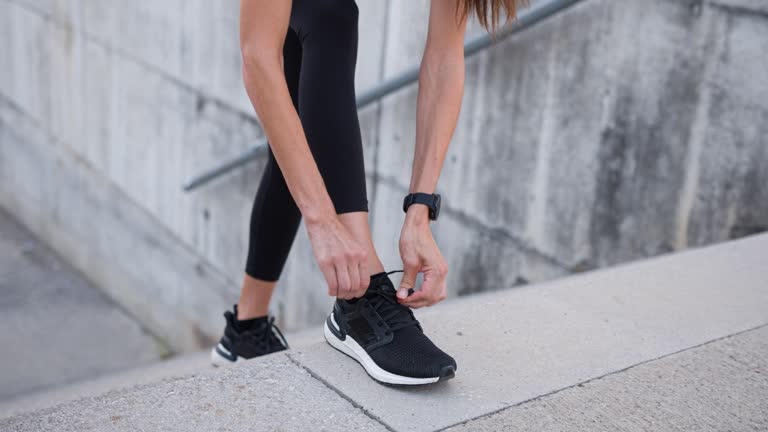 Young fitness woman tying shoelaces on sports shoe, getting ready for run