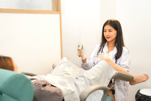 scena, w której ginekolog ma na sobie rękawiczki medyczne i przeprowadza badanie wewnętrzne pacjentki lub kobiety w ciąży, która leży na fotelu ginekologicznym w gabinecie zabiegowym - cytologia zdjęcia i obrazy z banku zdjęć