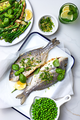 Baked dorado fish with gremolata, italian herb condiment, and grilled green vegetables