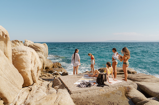 Photo of a group of smiling and cheerful young women spending their summer vacation by the sea