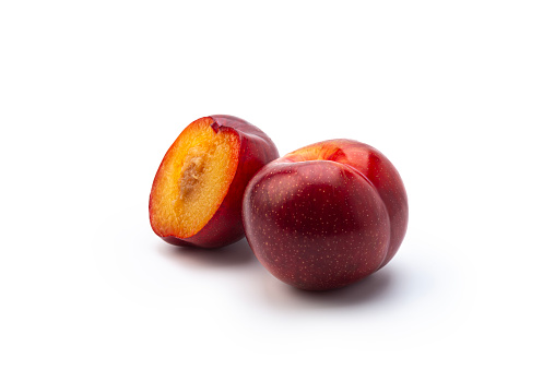 Fresh red plums isolated on a white background.\nHigh angle view, Studio shot: One whole, one slices.