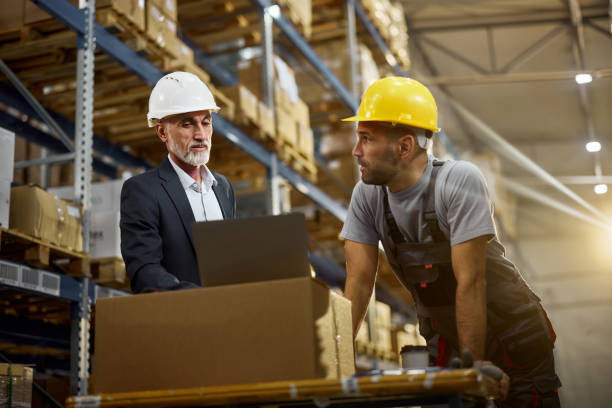 istock Senior manager and worker working on laptop in distribution warehouse. 1997449498