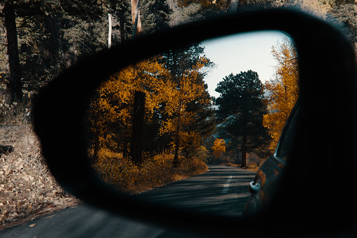 A scenic view of fall trees viewed through rear view mirror in Colorado