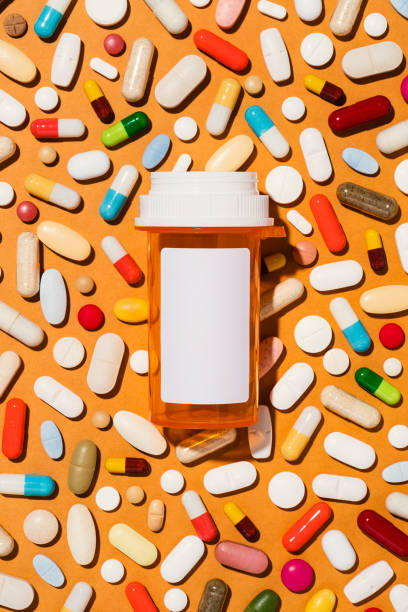 istock Medicine bottle with blank label on orange background covered in pills 1997467093