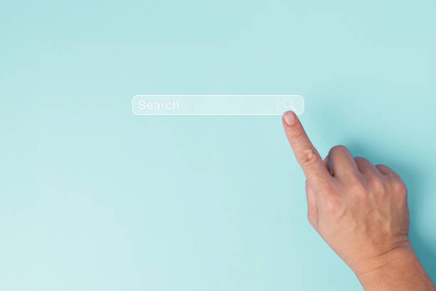 istock A single human hand is captured pointing to a virtual search bar on a plain pastel blue background, symbolizing the action of online searching, digital inquiry and research concept. 1997488523
