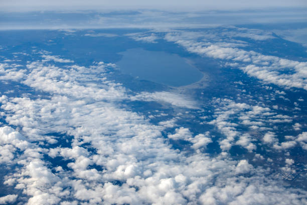 Aerial view of sky and clouds from above seen through the aircraft window, travelling by plane, magnificent breathtaking view during flight high through the cumulus clouds