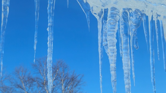 The icicles hanging from a roof against a clear blue sky