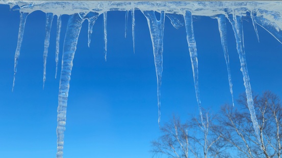 The icicles hanging from a roof against a clear blue sky