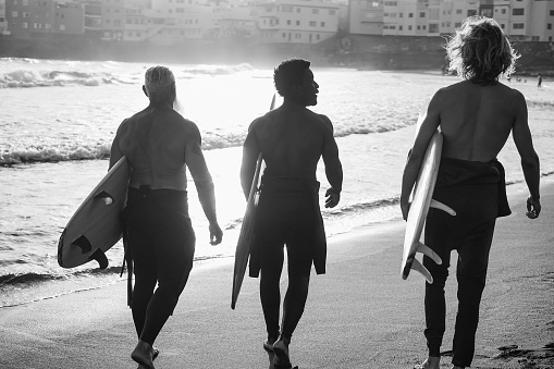 Multi generational surfer men having walking on the beach before surf session - Multiracial people, lifestyle and sport concept - Focus on center african male head