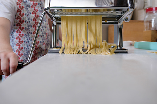 homemade fresh pasta cutting by machine, Tagliatelle machine in action.