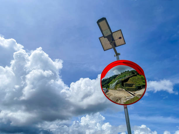 Curved road convex mirror hanging on a pillar with solar powered lamp