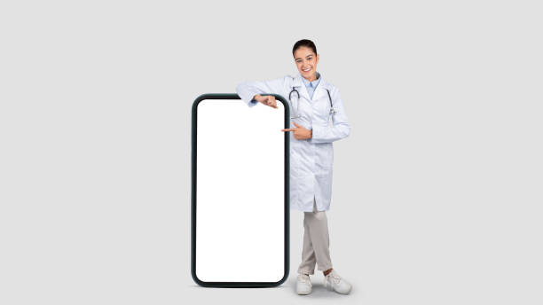 istock A cheerful young european doctor in a lab coat points to a blank smartphone screen 1997510406