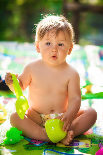 baby boy sitting in the garden and playing with water toys - swimming pool one baby boy only toddler image type стоковые фото и изображения