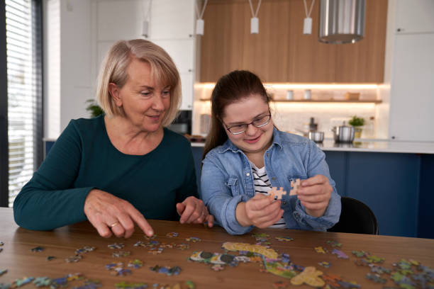 istock Focus down syndrome woman and her mother assembling puzzles at home 1997510962