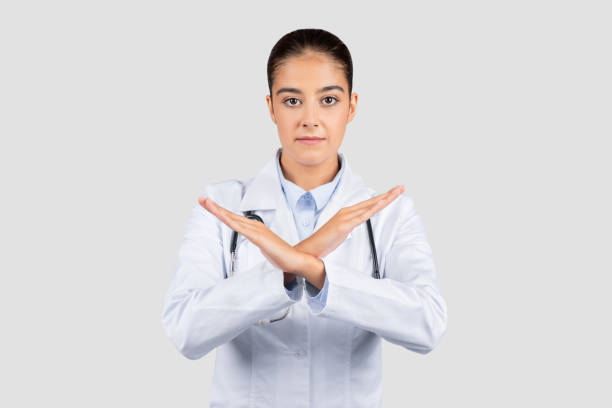 istock Caucasian millennial doctor with a serious expression making an 'X' sign with her arms 1997512601
